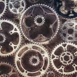 A close-up of various metallic gears arranged in an abstract pattern.