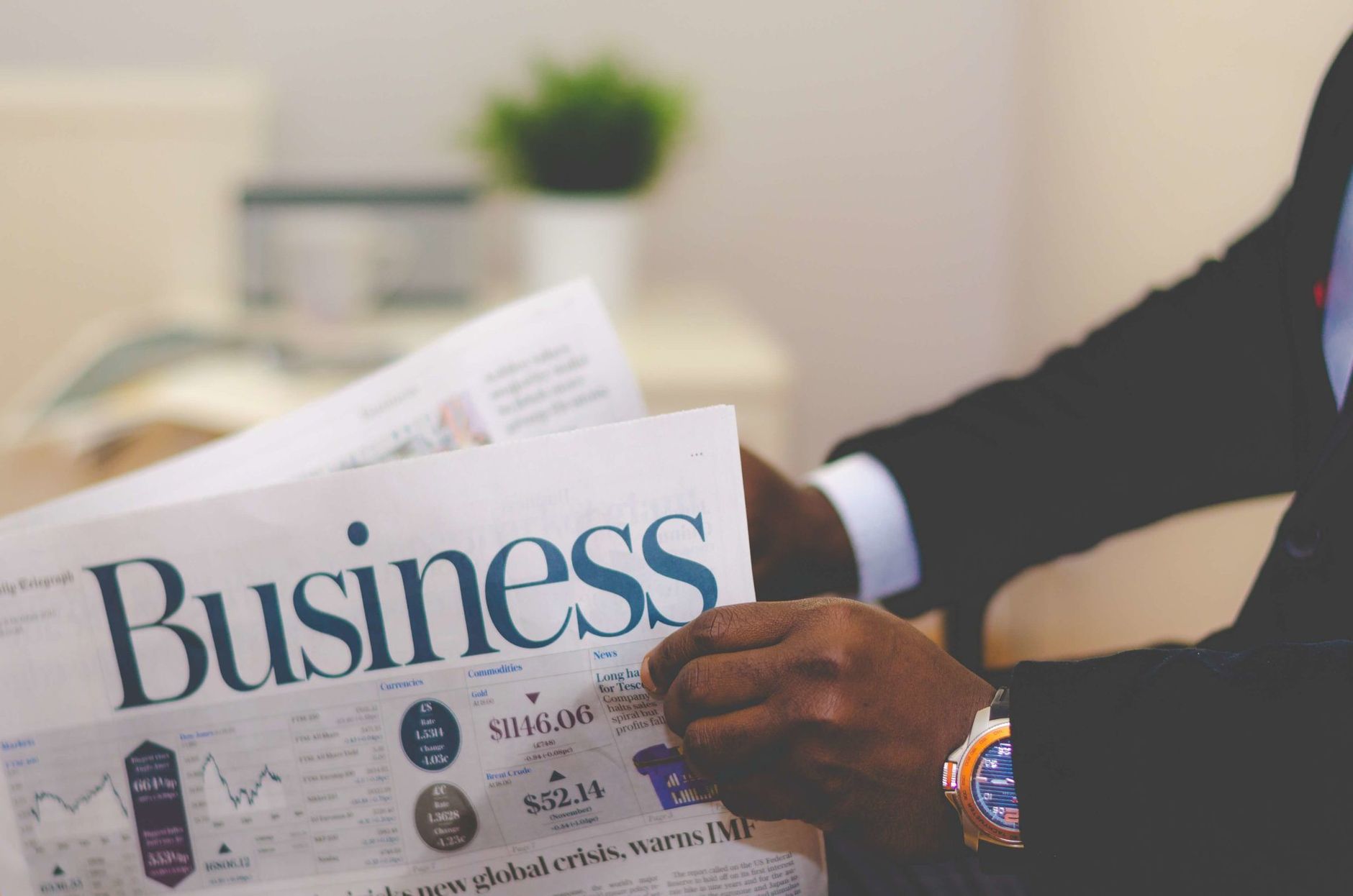 Close-up of a businessman reading a newspaper indoors, focusing on business headlines. — Dr Azfar Malik: Nationally Recognize