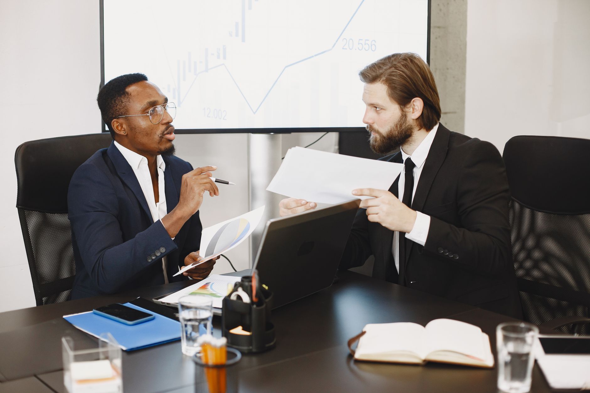 Two business professionals engaged in a planning meeting, discussing documents in a modern office setting. — "Enjoy Comfortab
