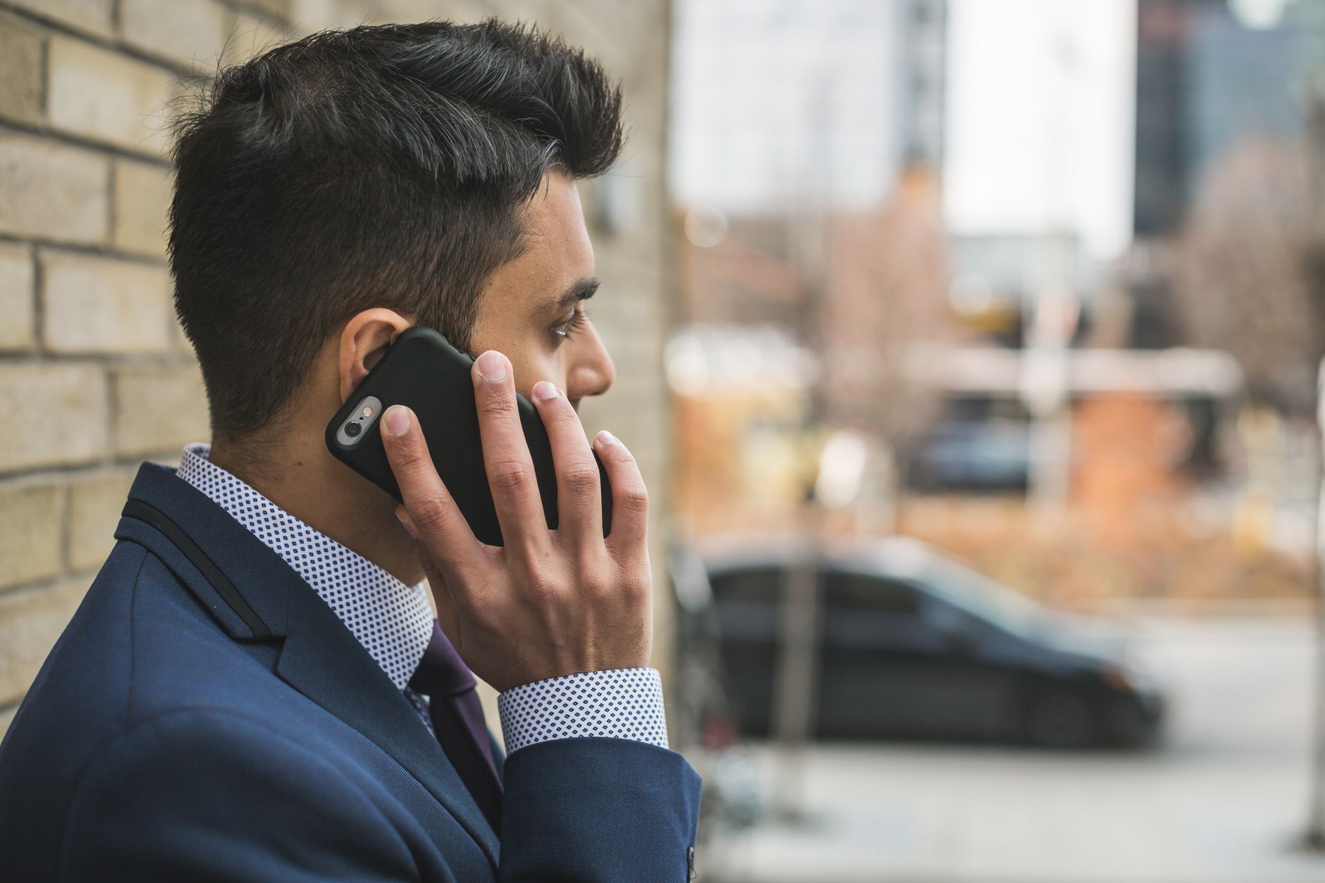 Professional man in suit making a phone call outside in city setting. — Find a Hospital Indemnity Insurance Plan Designed for