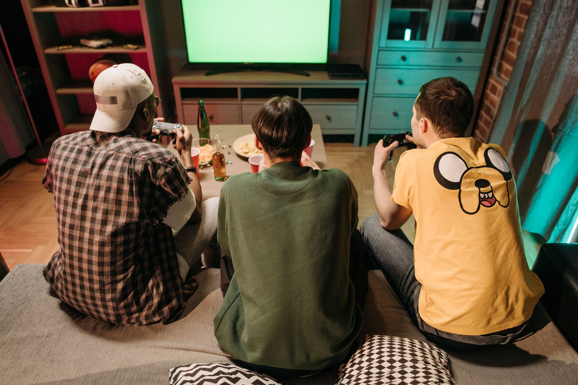 Three young men enjoying a home gaming session together, playing video games in a cozy indoors setting. — How Eat and Run Pol