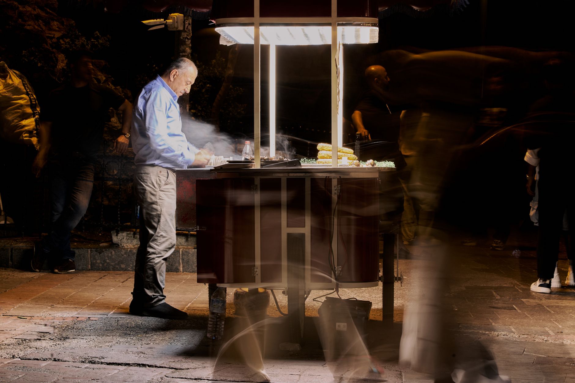Street vendor cooking food at night with blurred people passing by. — Kenton Crabb: A Leader in Strategic Financial Planning