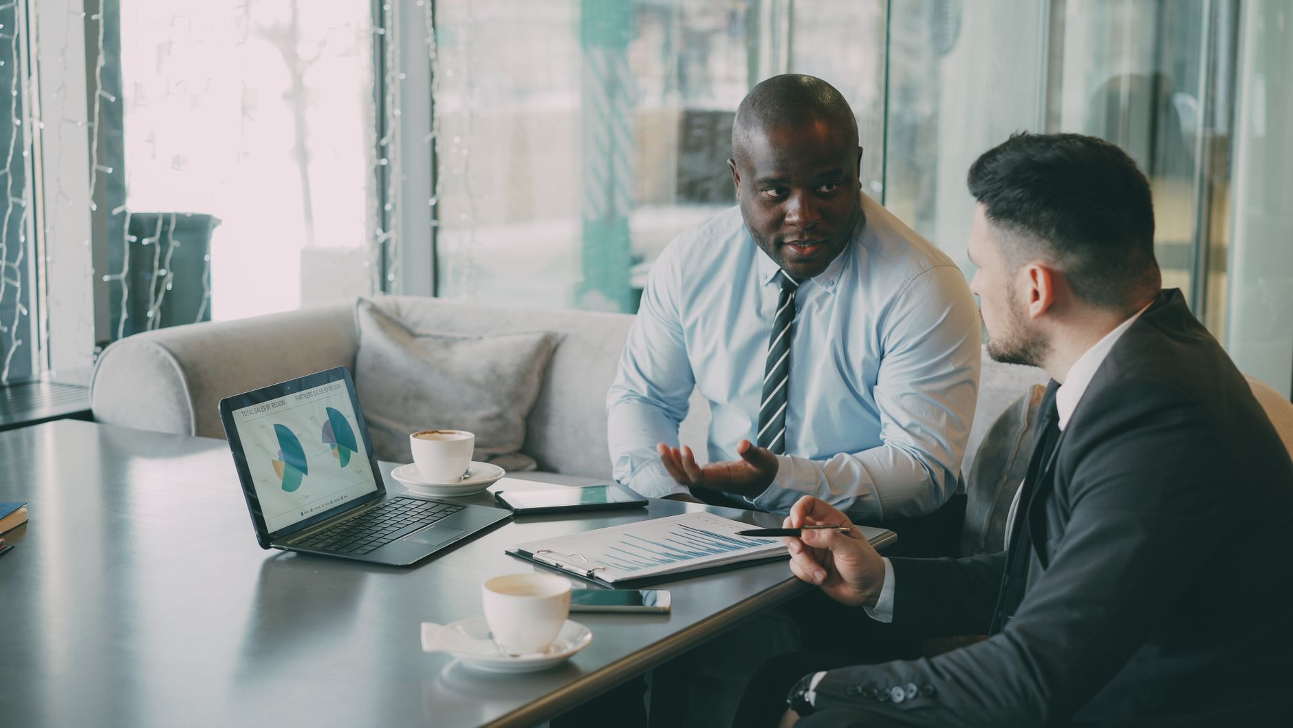 Two business professionals engaged in discussion over laptops and documents. — Riverside Homeowners: How to Sell Your House f