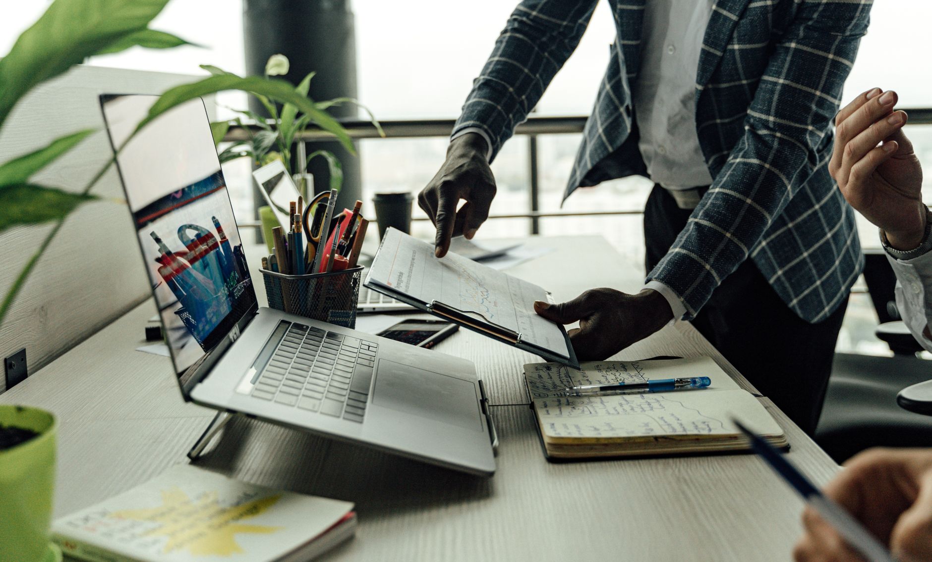 Colleagues collaborating on financial data analysis with a laptop in the office. — Roger Gallagher: Pioneering a Holistic App