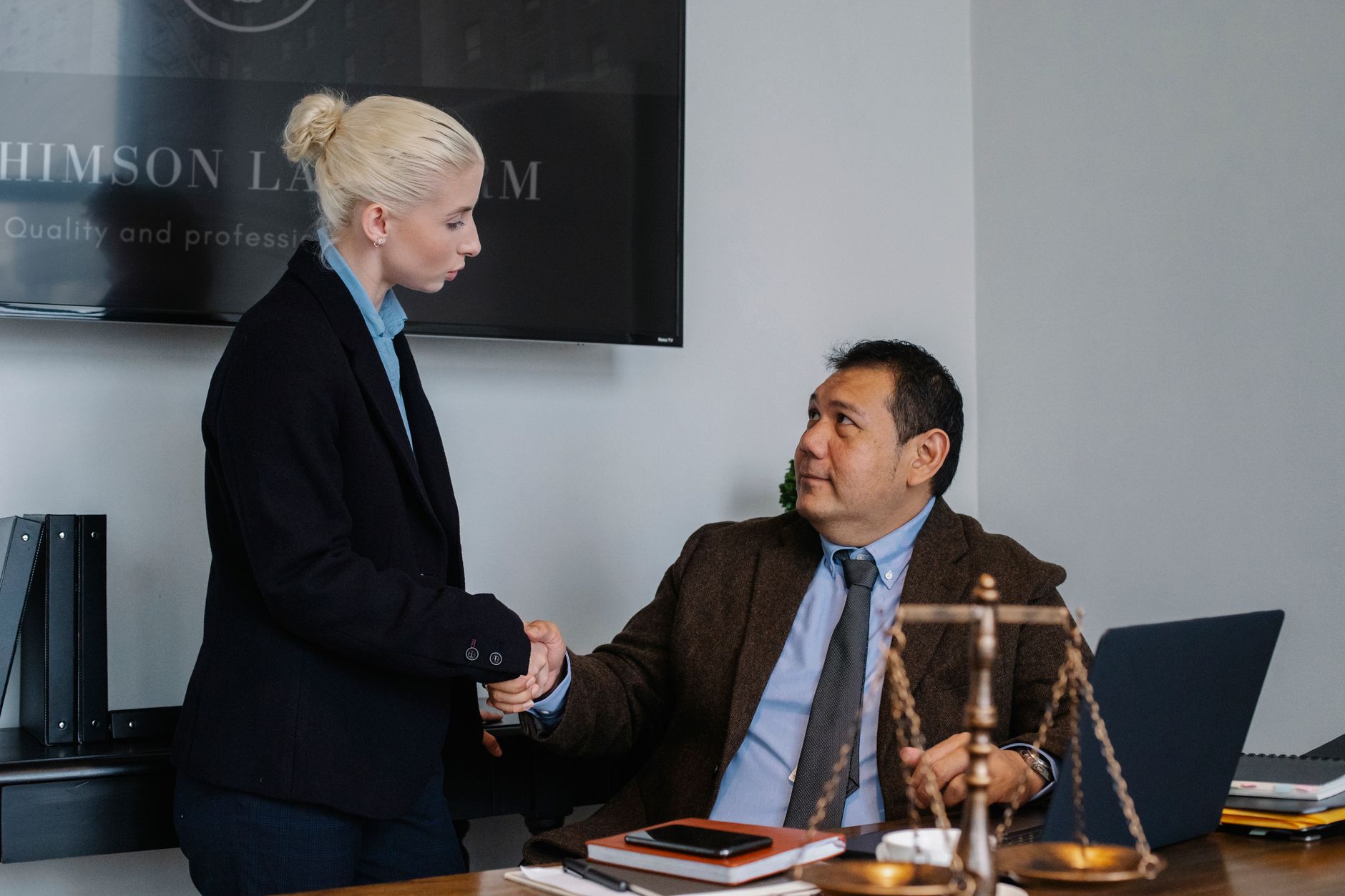 Multiracial coworkers in formal outfit shaking hands near table with scales of justice — Smart Governance Frameworks: Turning