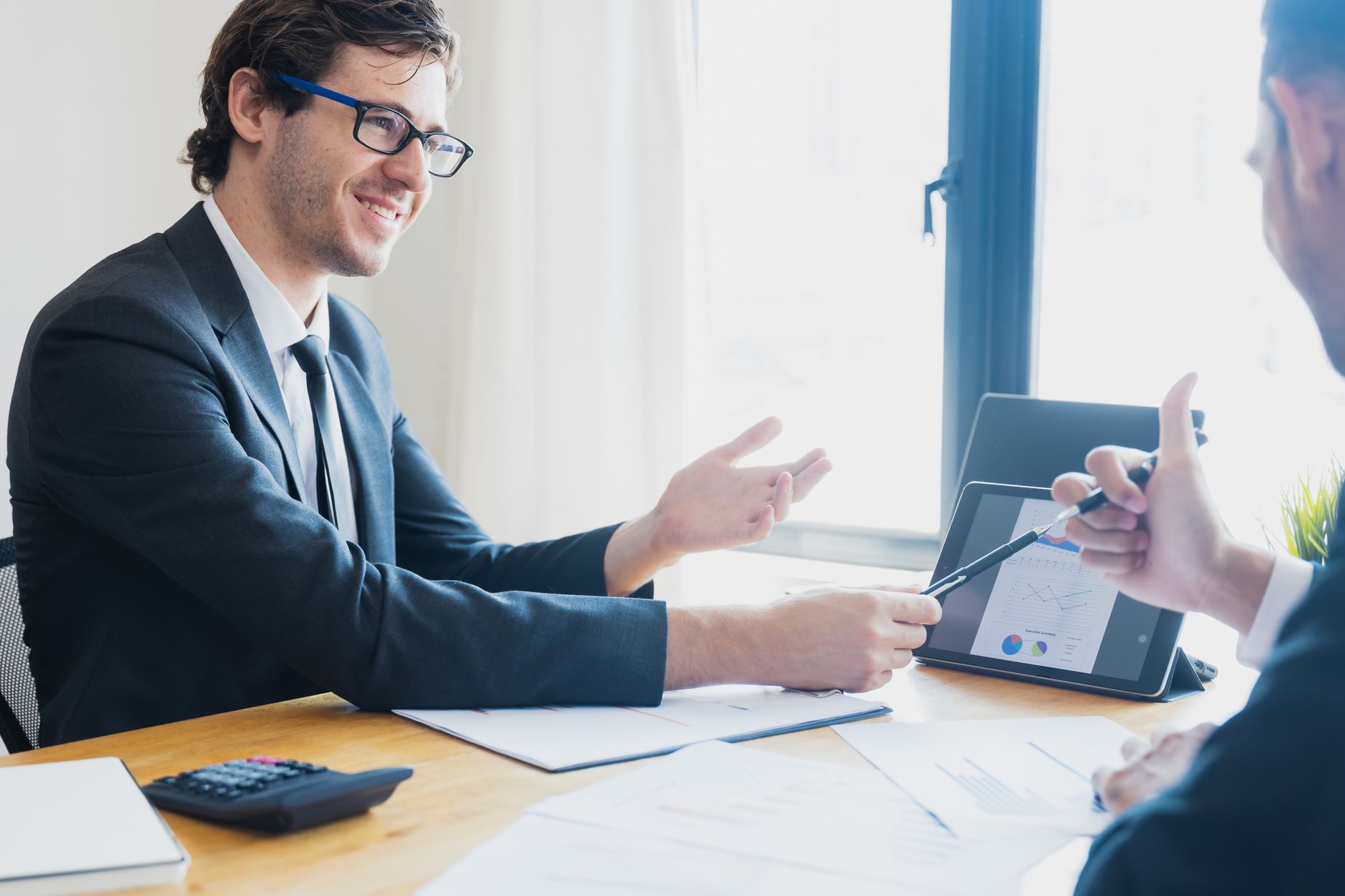 Two businessmen in formal attire discussing a business report in an office setting with a tablet. — Stay Organized: Use This