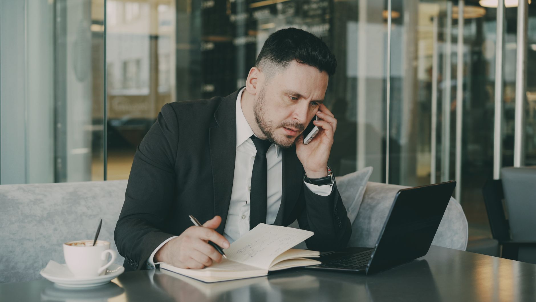 Businessman talks on phone while writing notes in a modern cafe. — Ultimate Madrid Pub Crawl: Best Bars and Pubs
