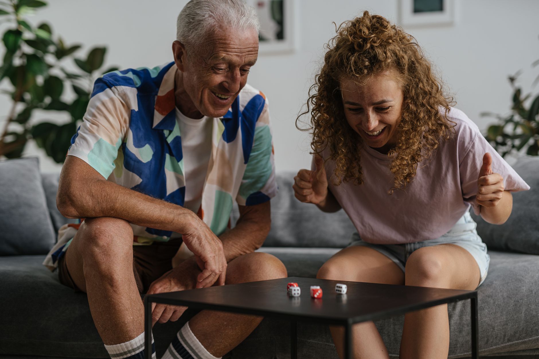 Elderly man and young woman enjoying a dice game at home. Laughter and fun. — "Why Premier League Football Tickets Bring the